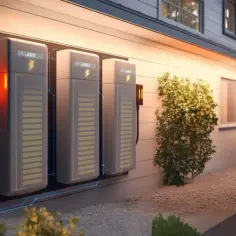 Nowoczesny magazyn energii do fotowoltaiki 10 kW, zamontowany na ścianie domu, otoczony zielenią.