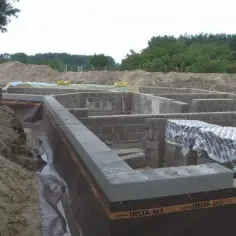 Fundament domu z bloczków betonowych, z widoczną izolacją. Solidna konstrukcja z keramzytobetonu zapewni trwałość.