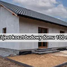 Tanie domy w budowie: szary, nieotynkowany budynek z ciemnym dachem i drewnianymi oknami.