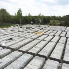 Budowa stropu gęstożebrowego z pustaków betonowych. Pracownicy układają elementy konstrukcyjne, przygotowując budynek do dalszych prac.
