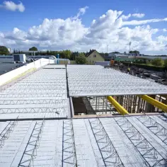Budowa dachu z prefabrykowanych elementów, ukazująca różne rodzaje stropów w trakcie montażu.