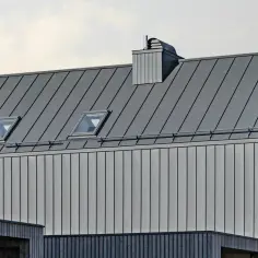 Nowoczesny dach z blachy na rąbek, z oknami połaciowymi i kominem. Sprawdź blacha na rąbek cena m2.