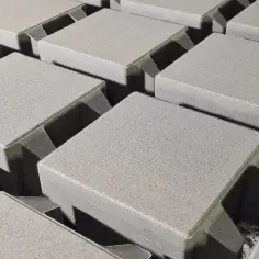 Szare, betonowe kostki brukowe ułożone w rzędach. Różne rodzaje kostki brukowej czekają na ułożenie.