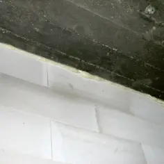 Piana montażowa wypełnia szczelinę dylatacyjną między betonowym stropem a ścianą z białych pustaków.