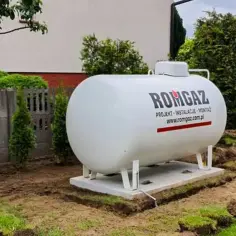 Nowy zbiornik na gaz płynny ROMGAZ, gotowy do zapewnienia ogrzewania gazowego z butli. Instalacja w ogrodzie.