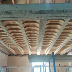 Widok od dołu na betonowy strop z pustakami ceramicznymi, tworzącymi charakterystyczny wzór.