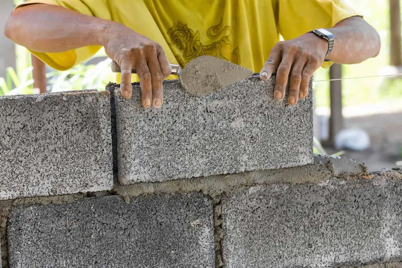 Murarz układa bloczki betonowe. Na m2 potrzeba ich ok. 12,5 sztuki, zależnie od wymiarów.