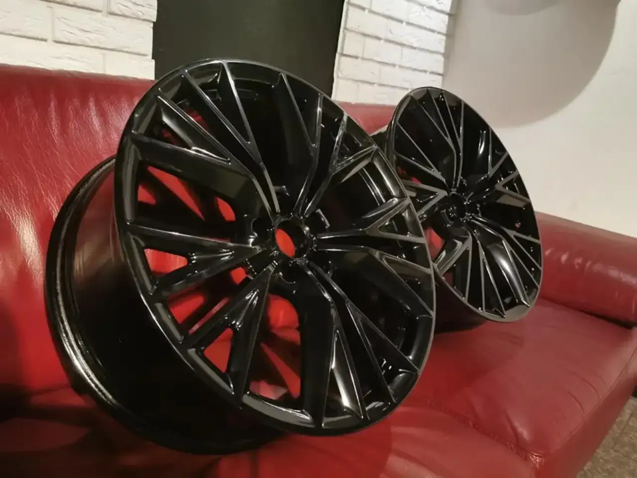 Dwa czarne felgi aluminiowe z czerwonymi wstawkami, idealne do tuningu. Dowiedz się, ile kosztuje malowanie proszkowe felg.