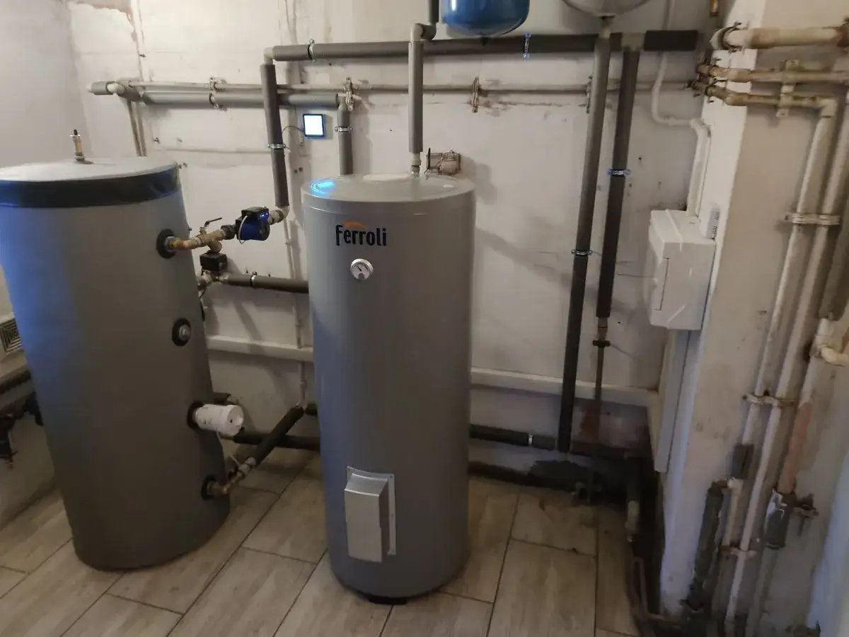 Dwa zasobniki wody, jeden z marką Ferroli, podłączone do instalacji grzewczej. To serce systemu, gdzie pompy ciepła zapewniają efektywne ogrzewanie, a ich koszt jest inwestycją w przyszłość.