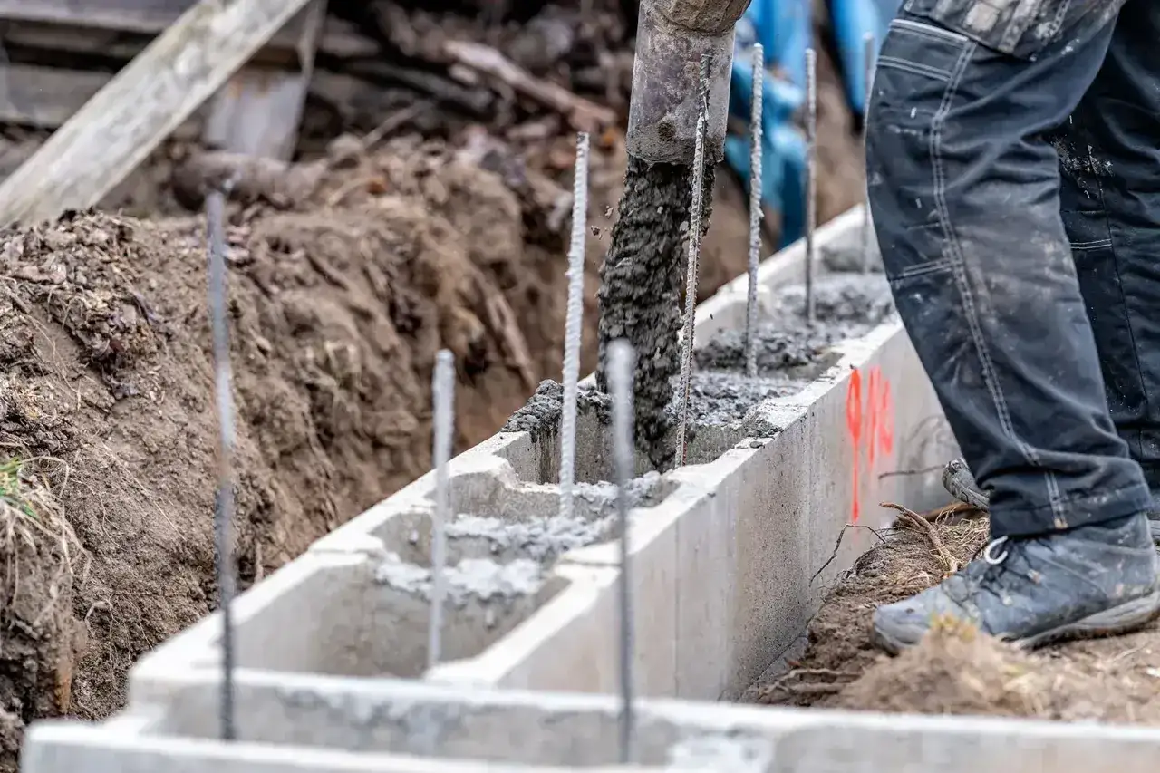 Betonarka wylewa beton do szalunku. Powstaje solidny kubik betonu, fundament pod budowę.