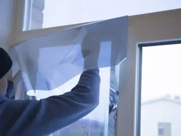 Nakładanie folii na okno, która przypomina efekt szkła weneckiego, nadając mu niebieskawy odcień.
