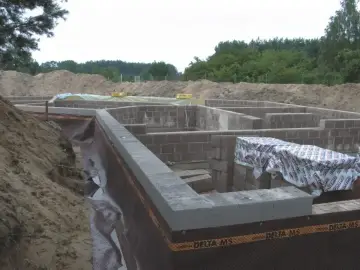 Fundament domu z bloczków betonowych, z widoczną izolacją. Solidna konstrukcja z keramzytobetonu zapewni trwałość.